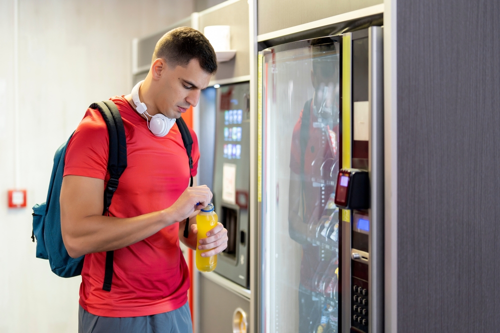 Athlete,in,gym,consuming,drink,from,food,vending,machine